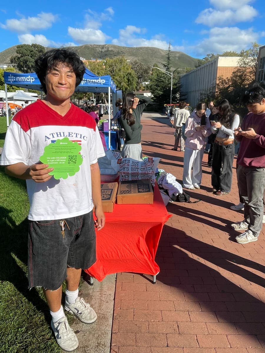 Student holding a QR offer card at a campus tabling event